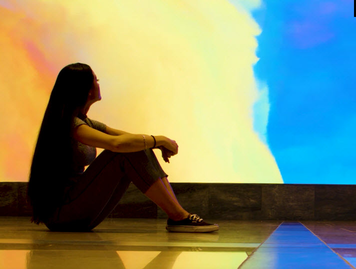 A woman sitting in front of the videowall.