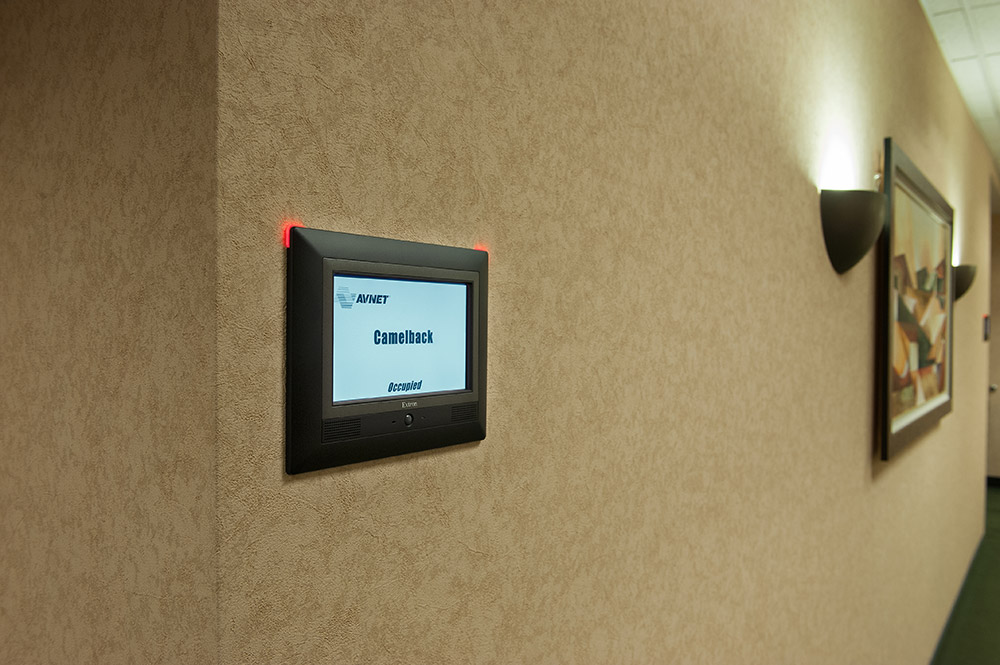 Touchpanels at room entrances are configured to indicate space availability.