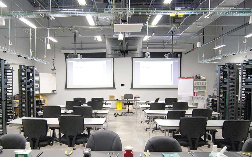 AV in training classrooms allows students to view table-top demonstrations on the projection screens without leaving their seats. Ceiling-mounted flat panel display faces instructor