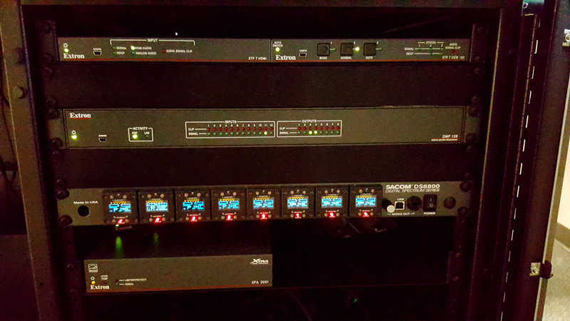 A rack in the control room with Extron extenders and audio products