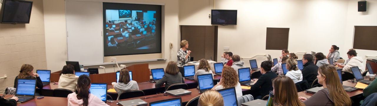 Classroom with teacher lecturing and students viewing projector screen