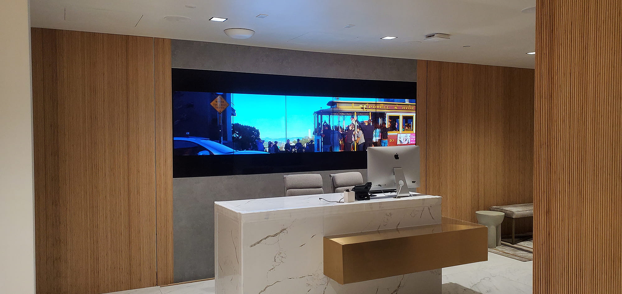 Espace d'accueil équipé d'un système de diffusion audio et vidéo synchronisée sur le mur d'images placé au‑dessus de la réception.