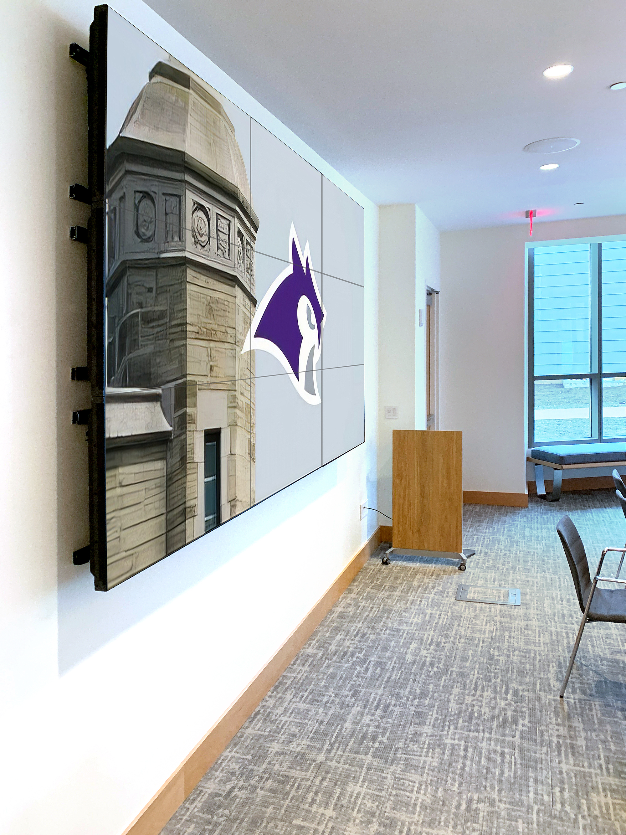 When a staff meeting or seminar is held in this Lowell House meeting room, the presenter sends content to the 3x3 videowall at the front of the room. The NAV scaling decoders with Extron WindoWall™ technology drive the videowall.