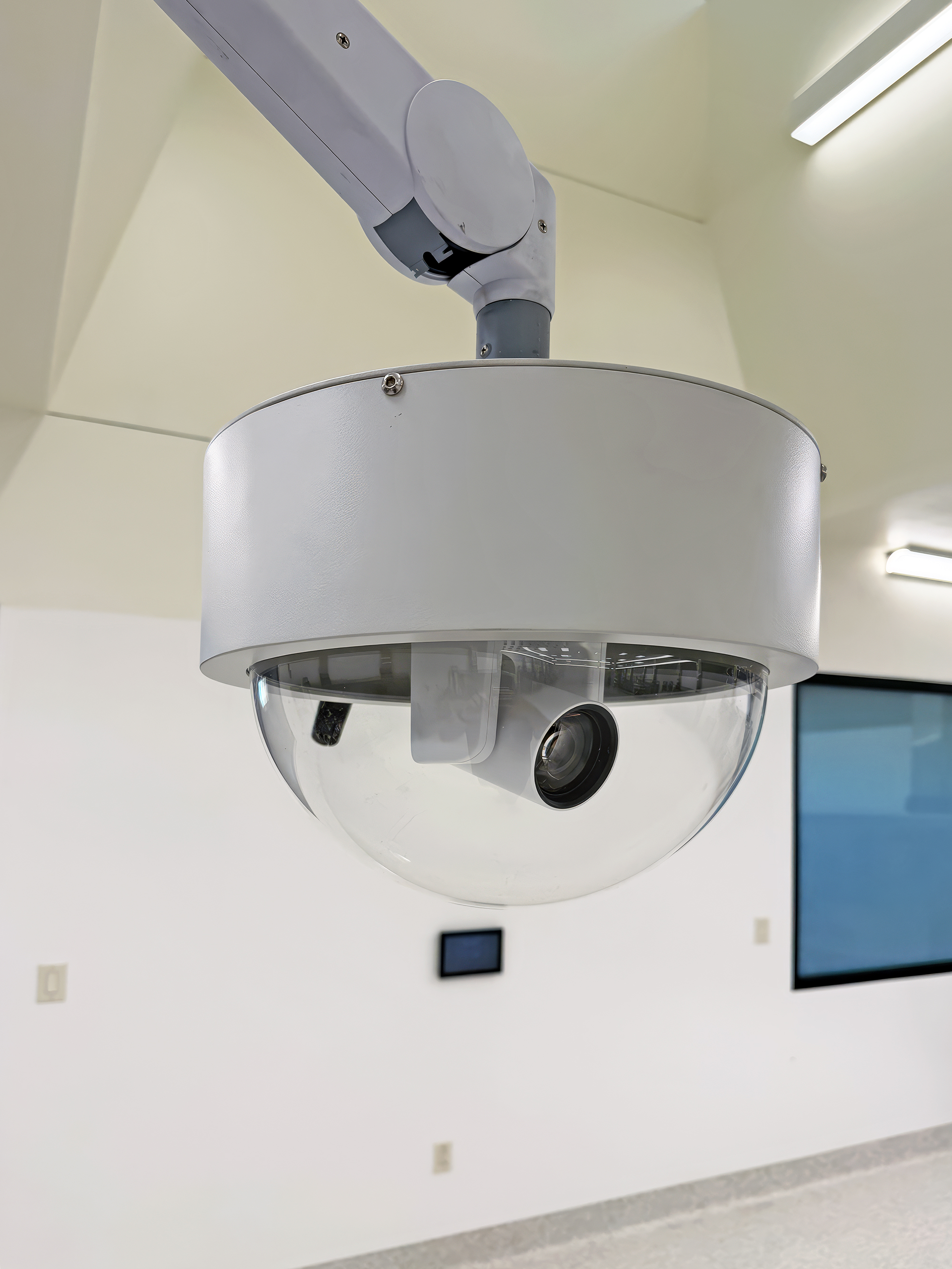 A ceiling mounted PTZ camera captures procedures for routing or recording. The wall mounted TouchLink Pro panel in the background provides simple control for camera selection and audio levels.