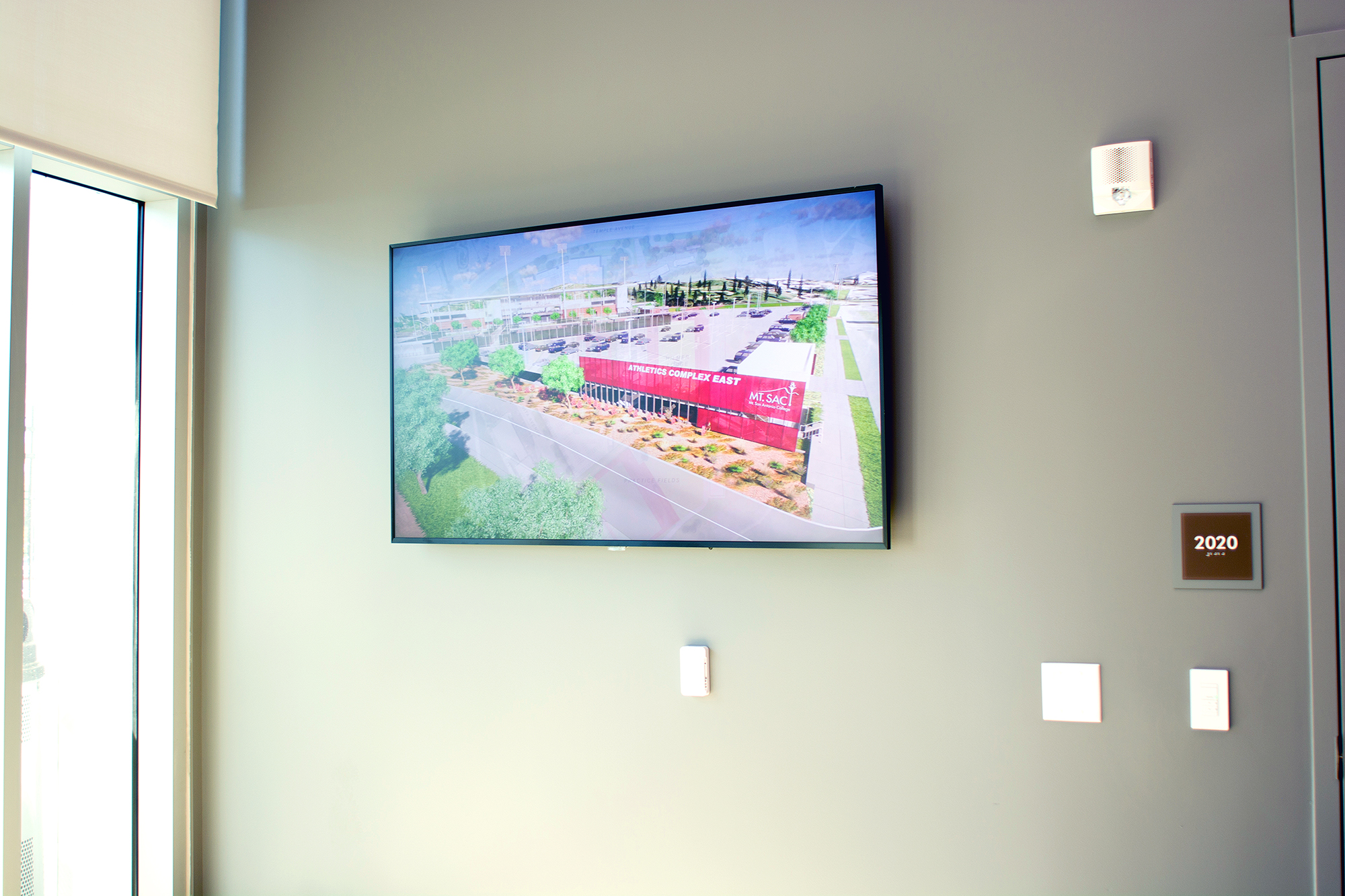 A display mounted on a side wall of the combination control room and press box allows easy monitoring of facility camera feeds and other selected content.