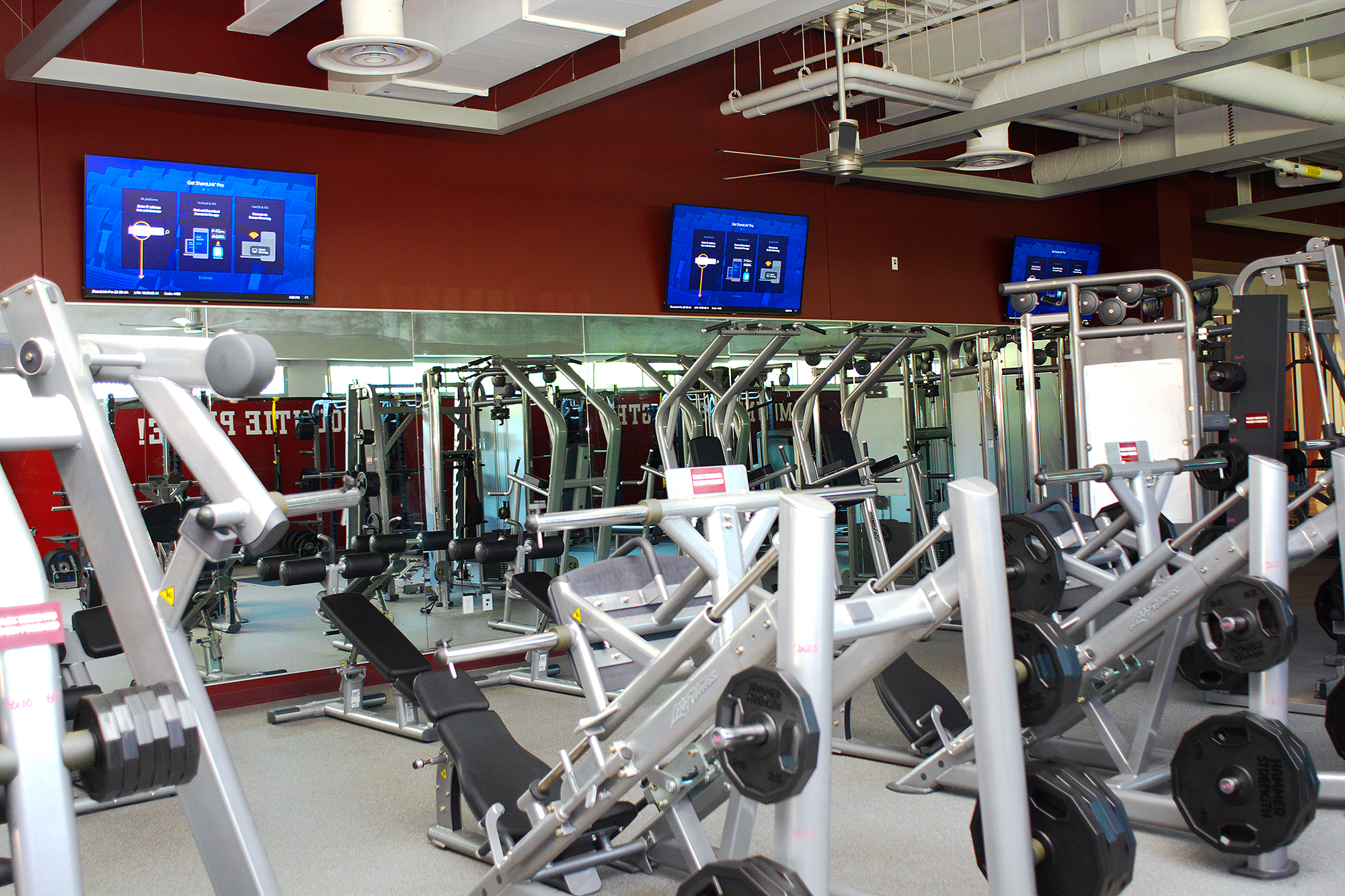 Spaces such as the weight room provide music and video content to entertain, inform, and encourage athletic endeavors in a variety of fields.