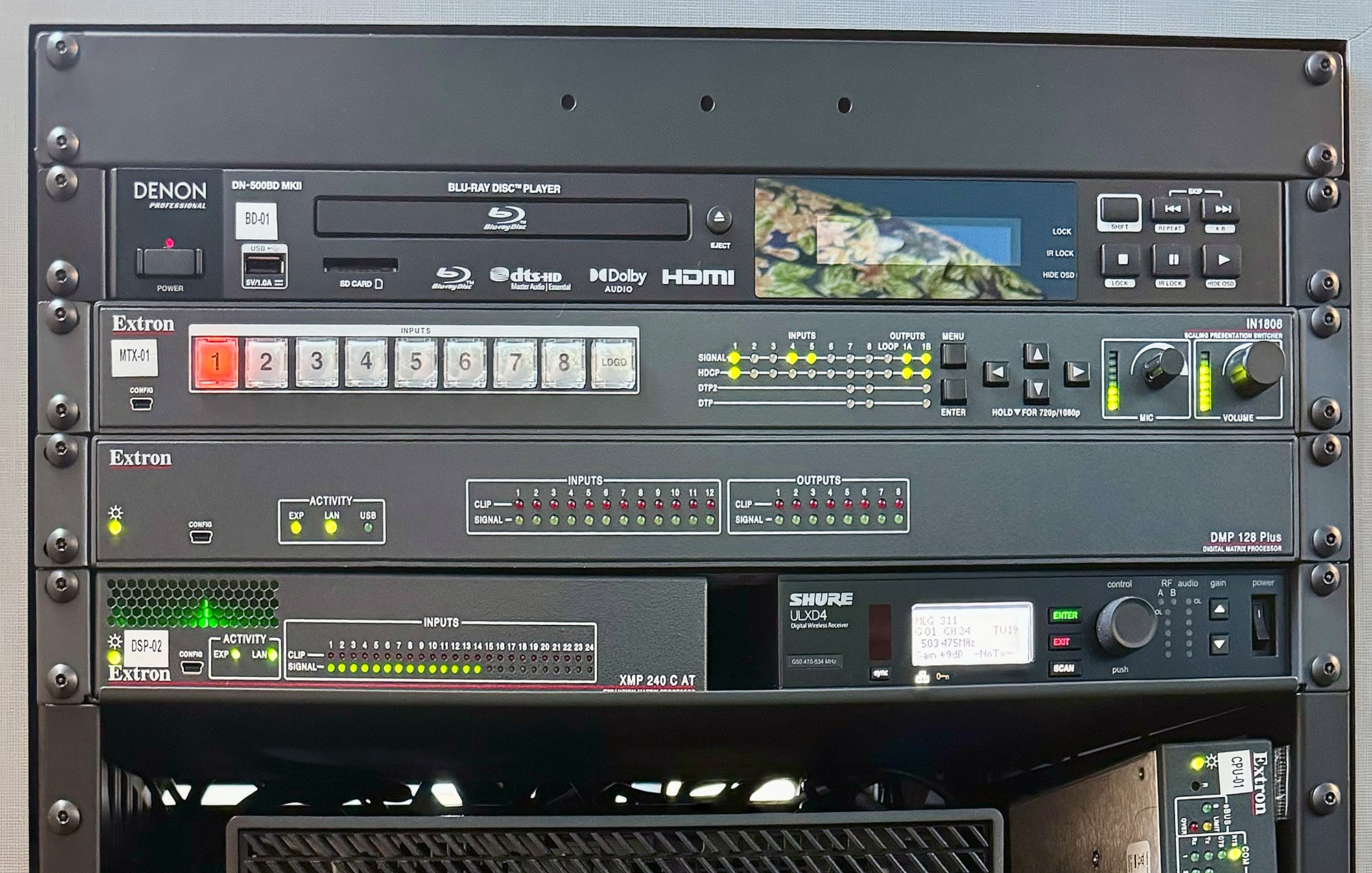 Vista detallada del equipamiento de Extron en las clases 301 y 311, y racks de equipamiento AV.