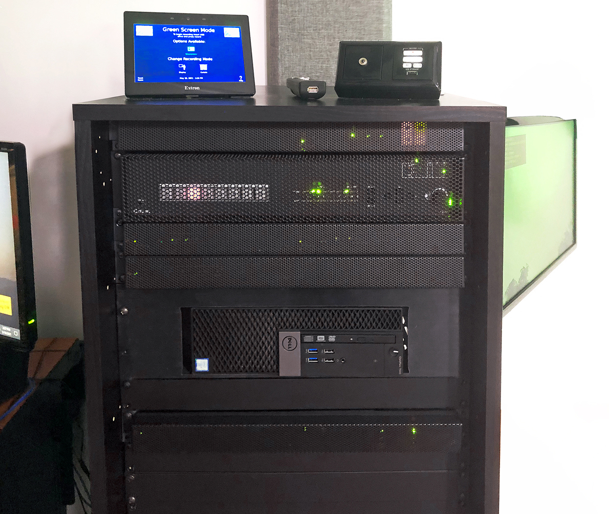 Main AV equipment rack. TLP Pro 725T 7" TouchLink Pro touchpanel, RCP 101 remote control panel, and presenter's remote control are on top of the rack. Visible within the rack are the IN1608 xi scaling presentation switcher and the PC. A confidence monitor swings out from the right side of the rack.
