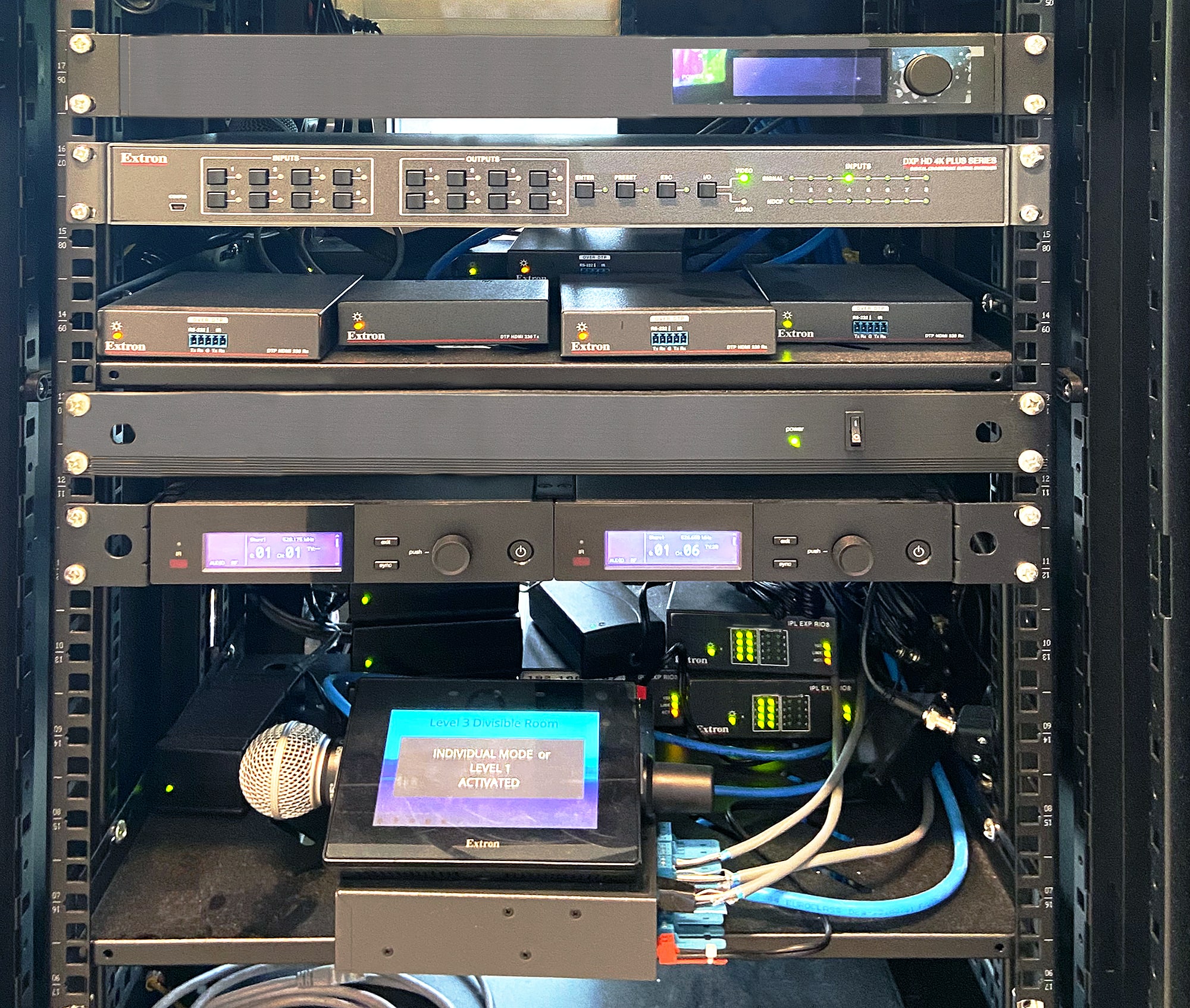 Rack de la salle divisible comprenant une grille de commutation DXP HD 4K PLUS, des extendeurs DTP HDMI 330, des interfaces d'expansion pour systèmes de contrôle IPL EXP RIO8, et un écran tactile TouchLink Pro Extron