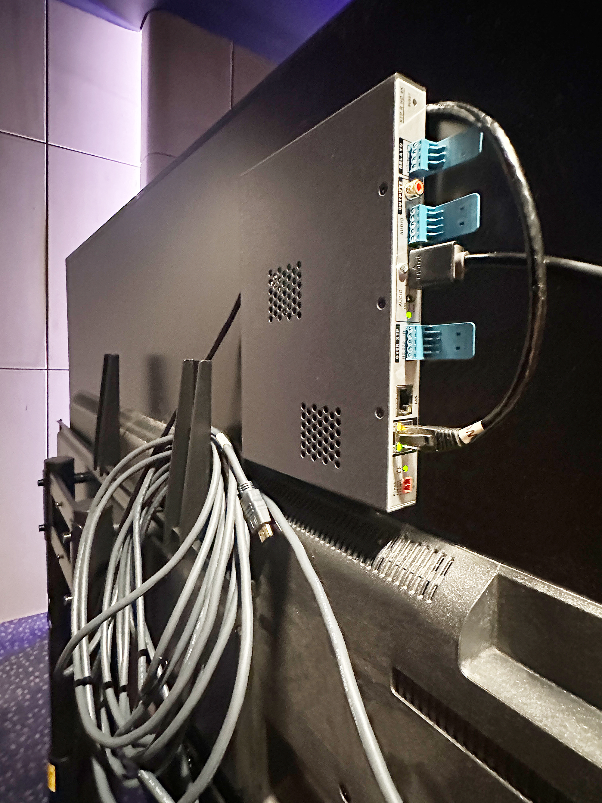 The low-profile enclosure of the Extron XTP R HD 4K receiver allows the unit to be installed discreetly, as shown here mounted behind a flat panel display.