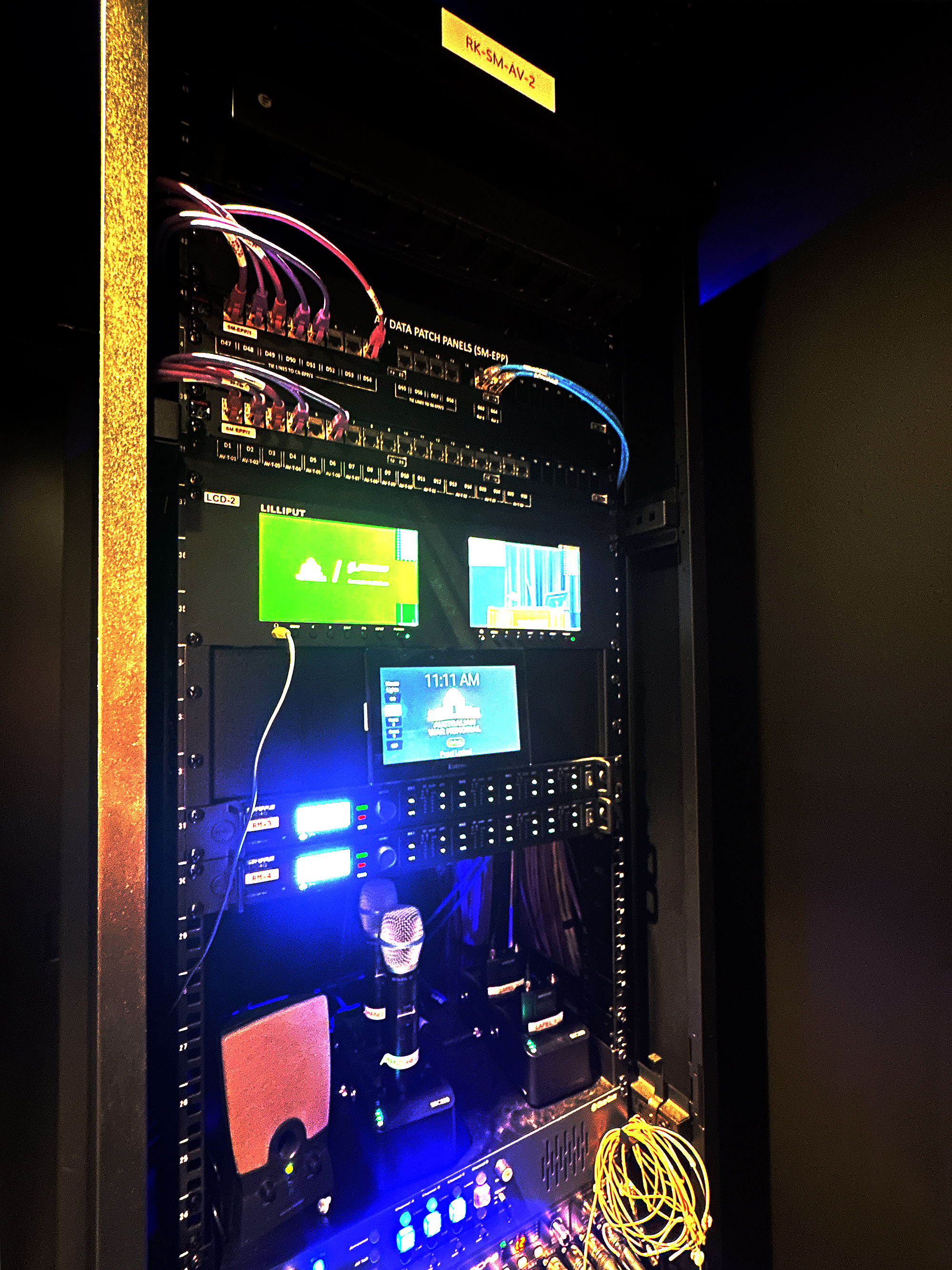 A Extron TLP Pro wall mount touchpanel is shown here mounted in one of the AV racks for easy source selection by a technician during an event.