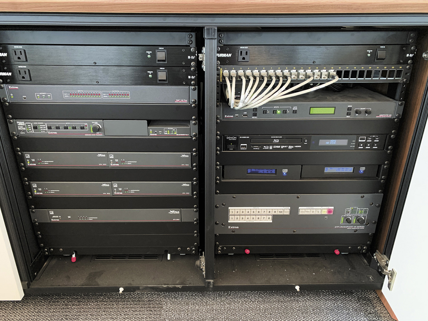 El armario de equipamiento de la clase aloja fuentes locales, junto con varios componentes de audio, vídeo y control de Extron como la matriz de conmutación para presentaciones DTP CrossPoint 4K.
