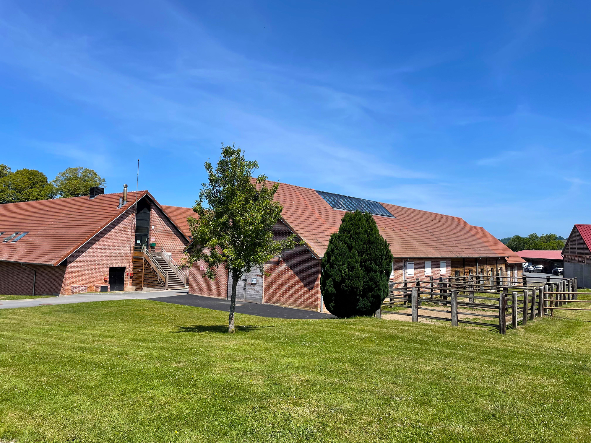 The architecture blends period farm structures with modern medical and training spaces, unified by a fiber-connected AV network.