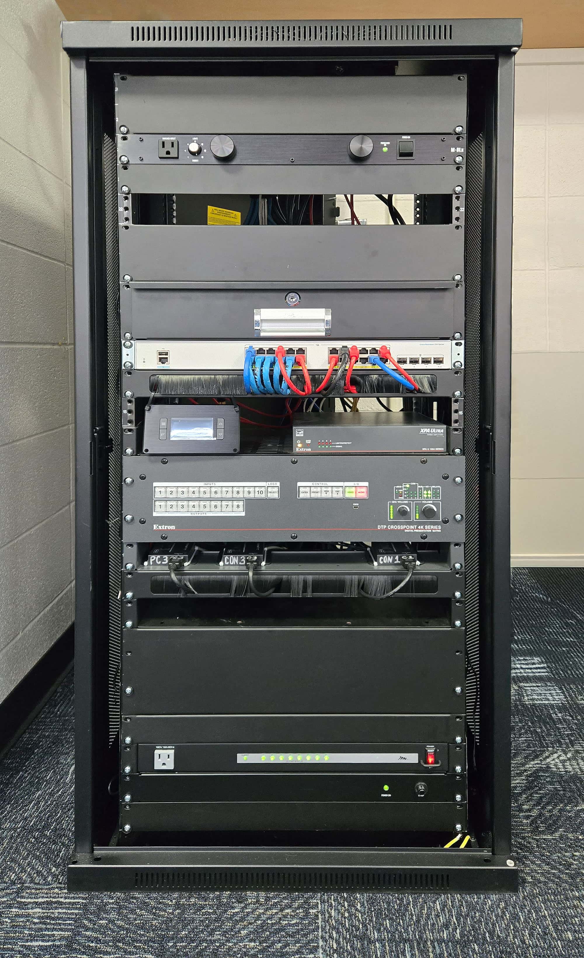 Composant central du laboratoire e-sport de l'ISU : baie audiovisuelle intégrant des équipements Extron dont la grille de commutation DTP CrossPoint 108 4K, un DSP audio, et des systèmes de contrôle pour un routage vidéo fluide et des performances à faible latence.