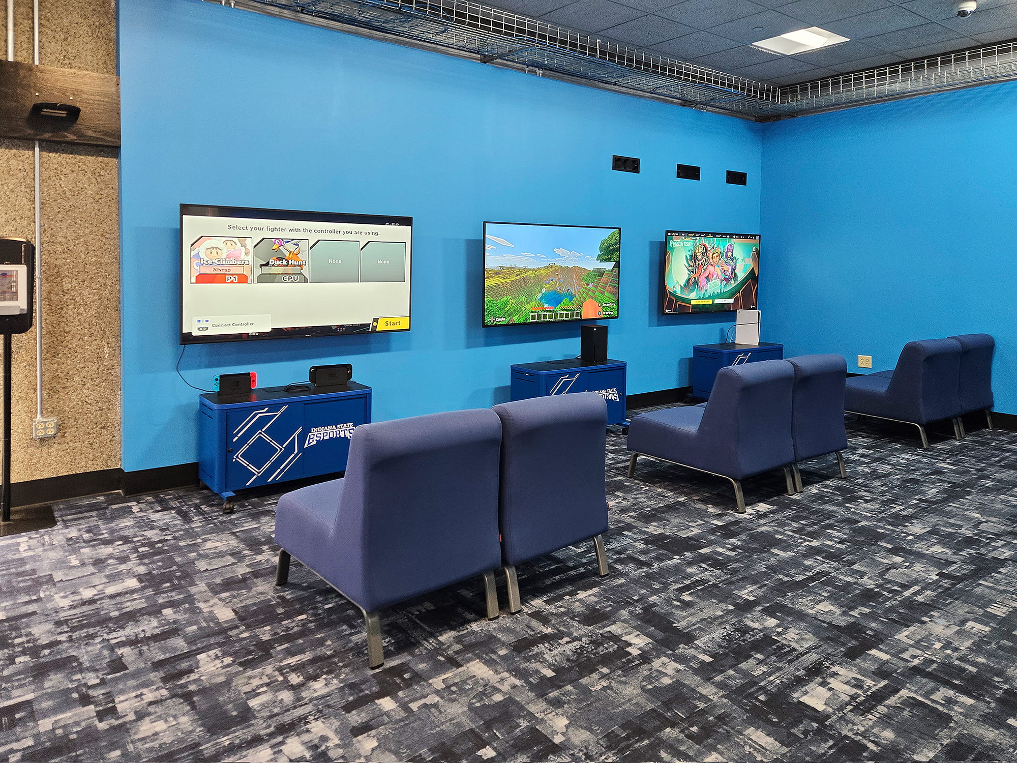 Espace détente du laboratoire e‑sport de l'ISU, équipé de stations de gaming avec consoles et de sièges confortables.
