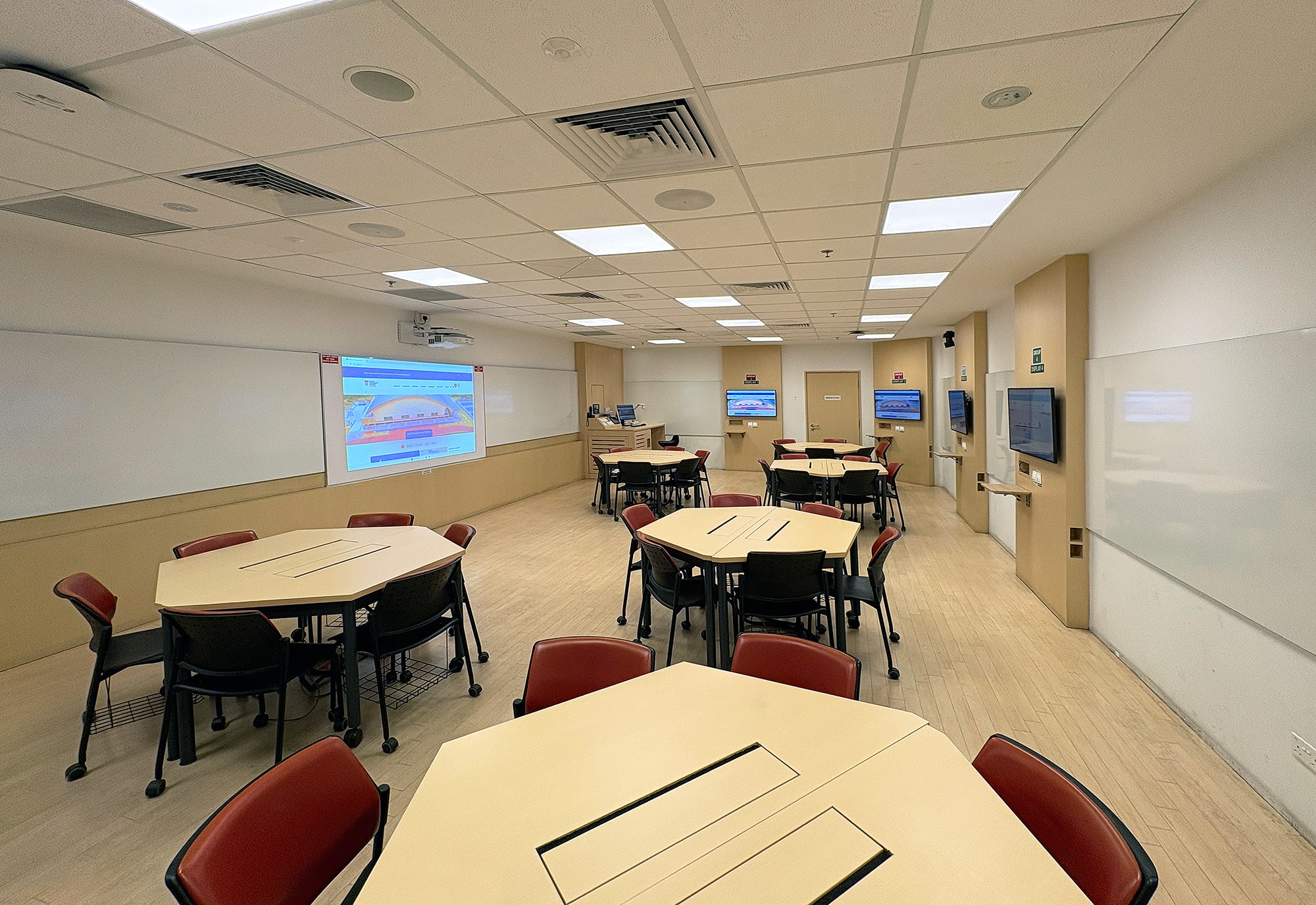 Prise sous l'angle opposé, cette vue montre comment les salles de tutorat de la NTU sont configurées pour les discussions d'équipe et le partage de contenu à partir de n'importe quelle table.