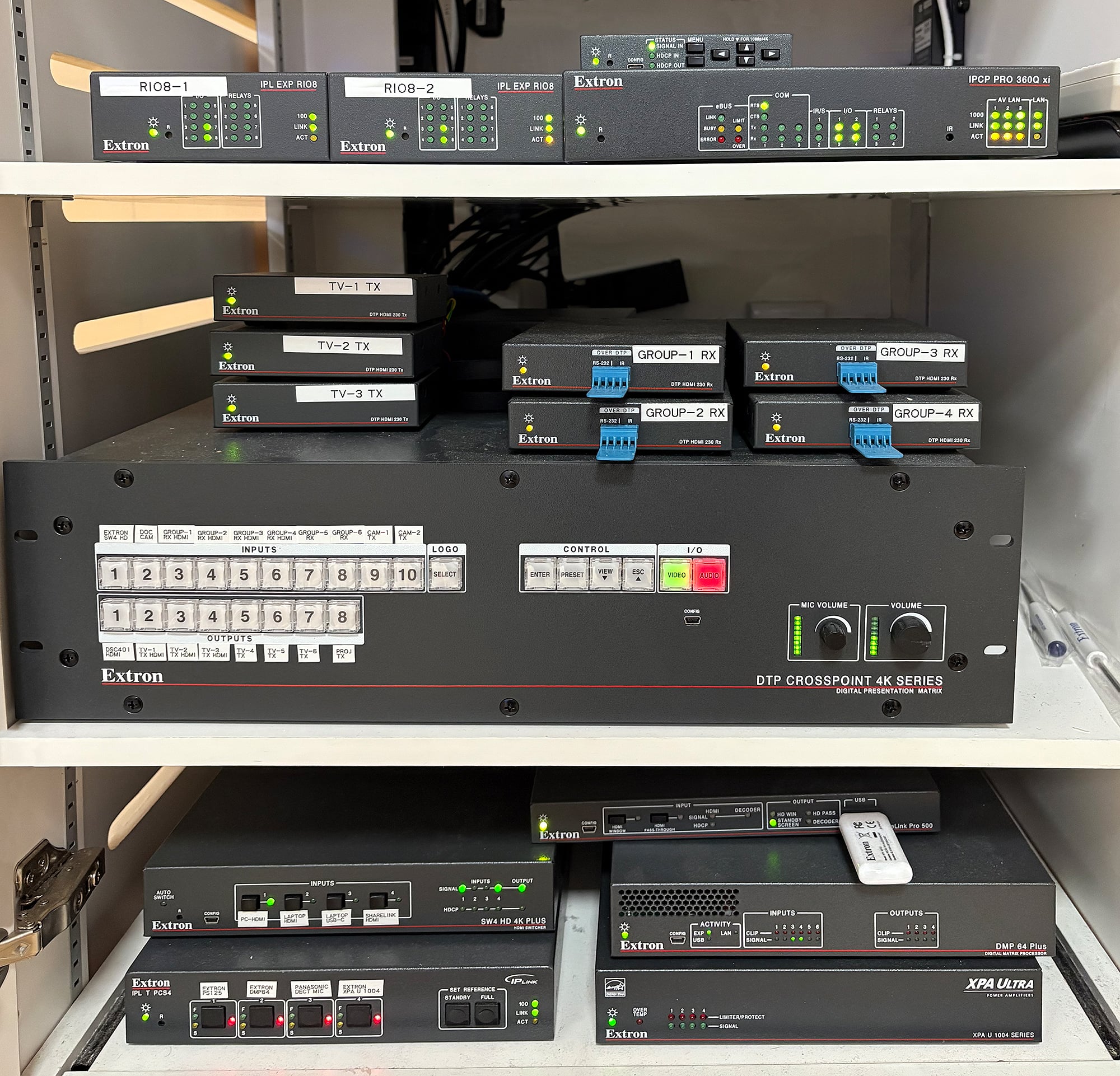 Un placard technique vu de l'intérieur disposant des composants de systèmes audiovisuels compacts Extron qui fournissent une commutation propre, un contrôle, et un traitement audio.