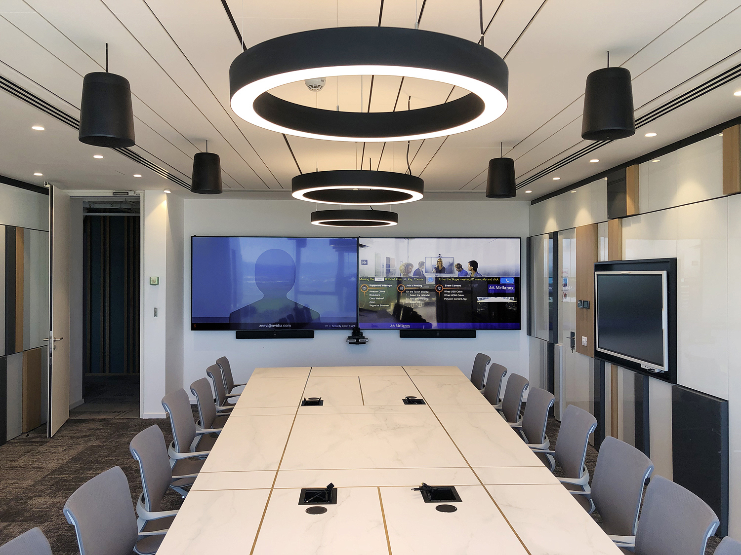 Jeder Meetingraum strahlt mit dem eleganten Konferenztisch, indirekter Beleuchtung und den schwarzen Extron SF 26PT-Hängelautsprechern schon beim Betreten des Raums eine professionelle Atmosphäre aus.