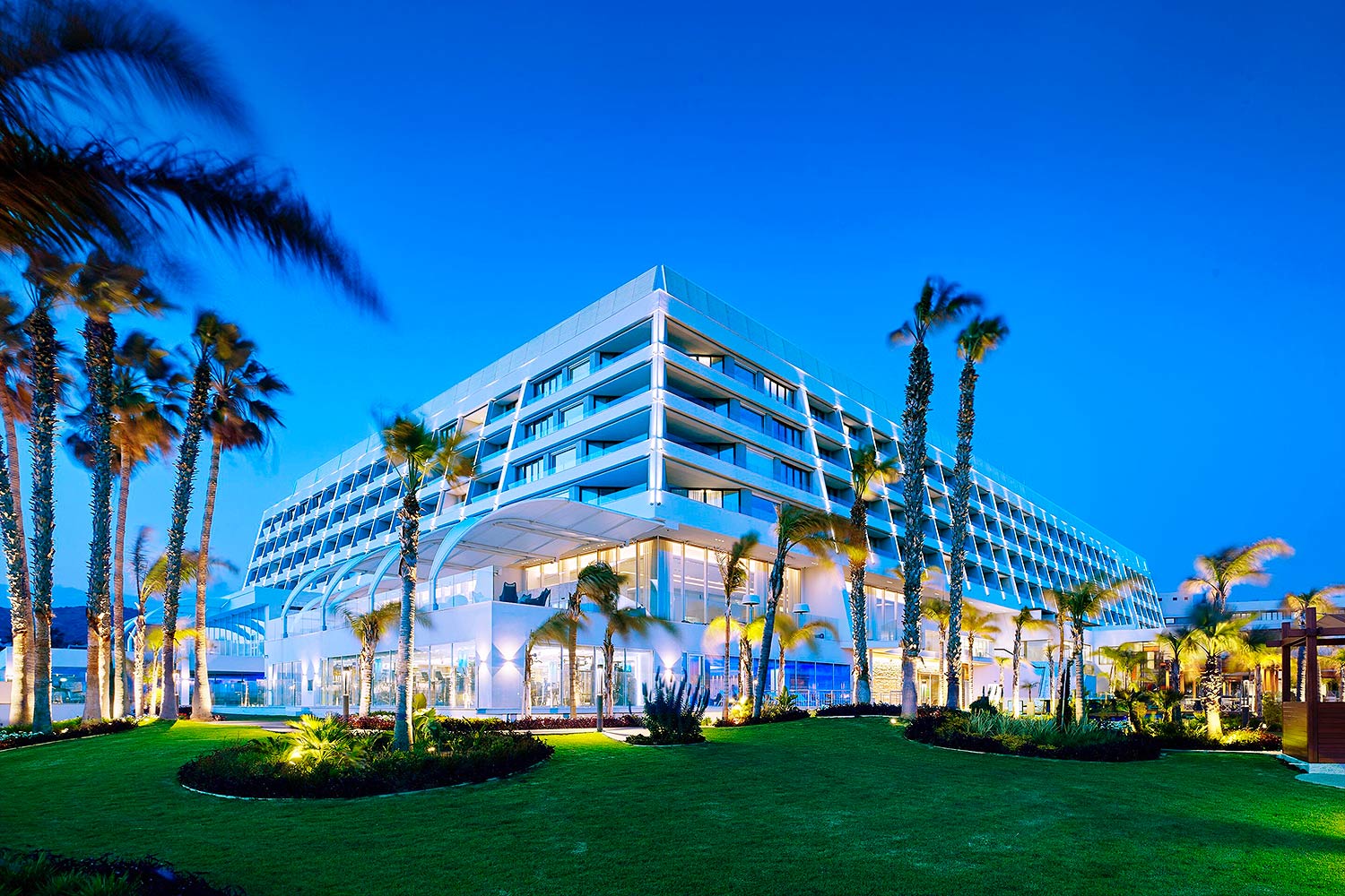Vue extérieure du Parklane Resort and Spa, vue en angle, entourée d'une pelouse et de palmiers