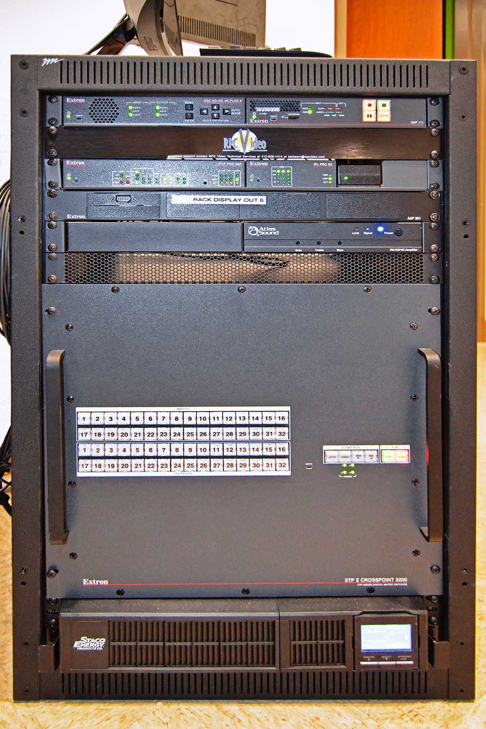 The XTP II CrossPoint 3200 matrix switcher and other system components are rack-mounted in the adjacent equipment room. This space is also used to store spare gaming gear and provides a small work space with a connected monitor.