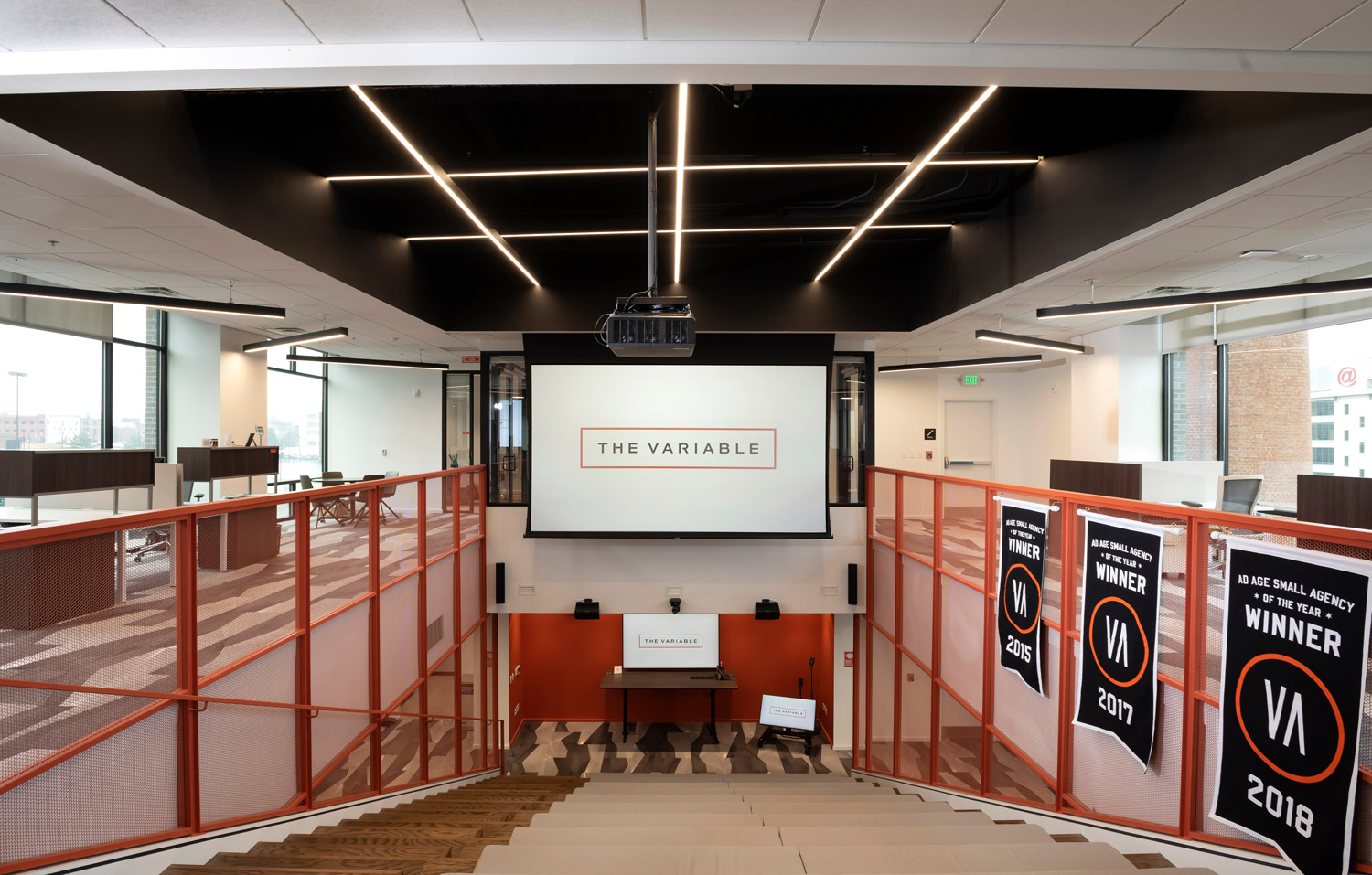 Ein Bürobereich über mehrere Ebenen mit einem Projektor an der Decke und einer Leinwand in der Mitte.