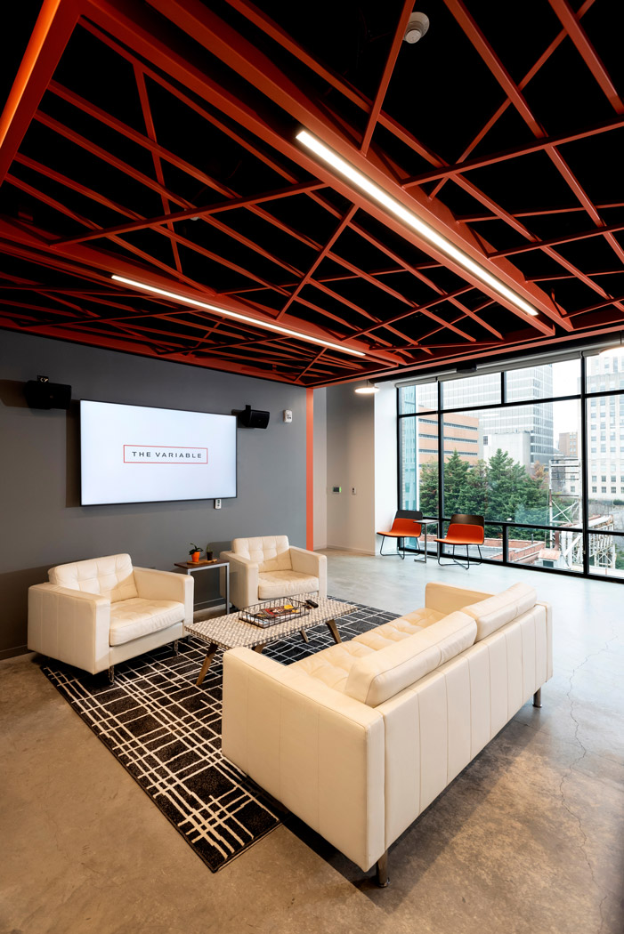 An office space with arm chairs, a couch, and a digital wall display.