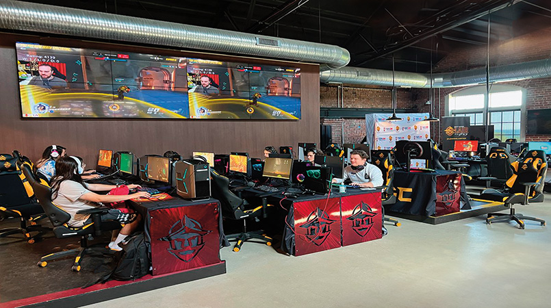 A filled Esports arena, with an active match running.