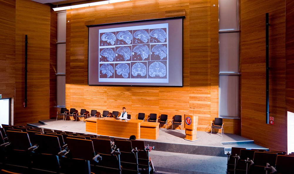 Un aula universitaria grande en una escuela de medicina con imágenes médicas proyectadas en la pantalla.